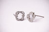 A pair of silver-toned post earrings with an openwork knot design set with small clear stones, displayed on a plain white background.